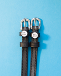 Black leather ManeJane spur straps with round OH SH*T charms on a blue background