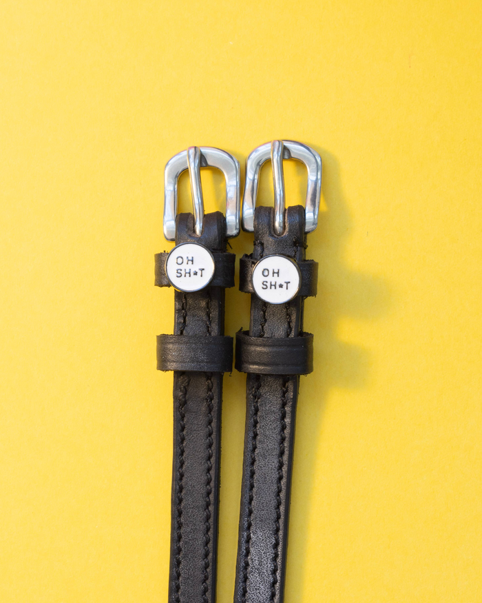 Black leather ManeJane OH SH*T spur straps on a yellow background