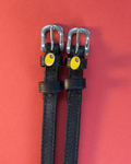Black leather ManeJane spur straps with green olive charms on a coral red background
