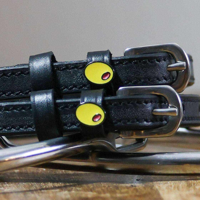Close-up of green olive charms with red pimento on black leather spur straps