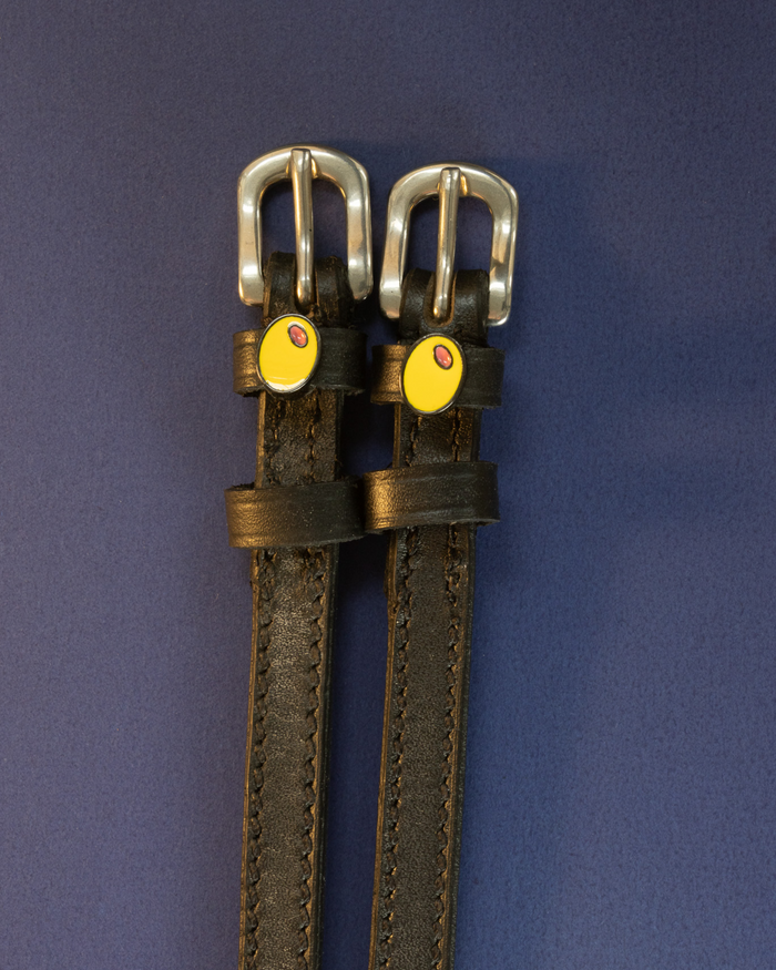 Black leather olive charm spur straps on a navy blue background