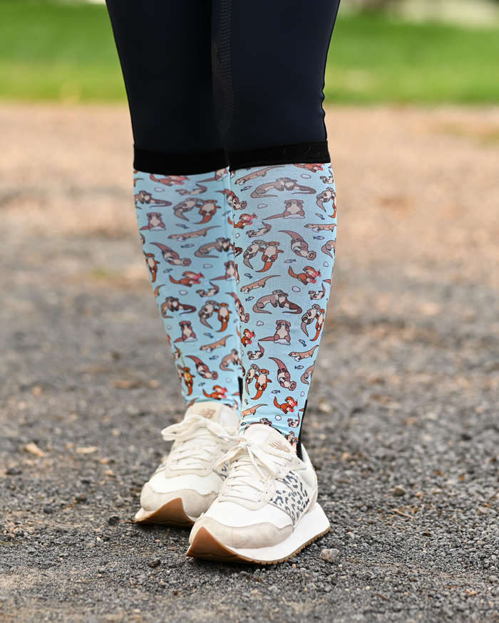 Otter-ly Adorable equestrian boot socks worn at the barn, pale blue with otters floating and holding hands