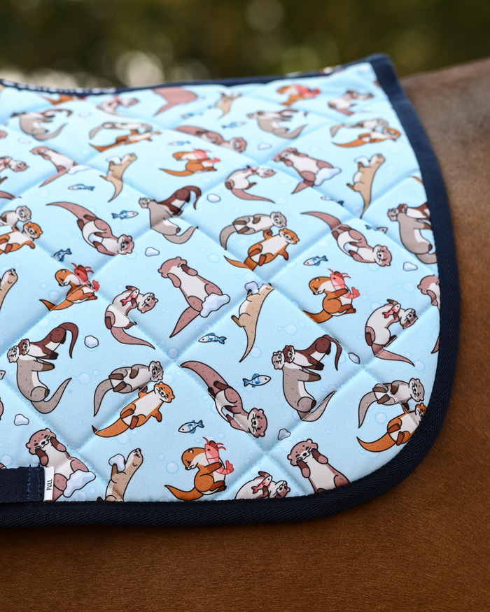 Close view of the Otter-ly Adorable print: floating otters and little fish on pale aqua, navy binding