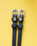 Black leather ManeJane spur straps with silver rhinestone owl charms on a yellow background