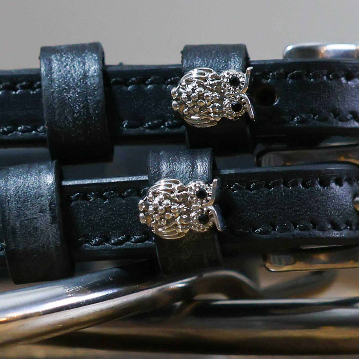 Close-up of sparkling crystal owl charms on black leather ManeJane spur strap keepers