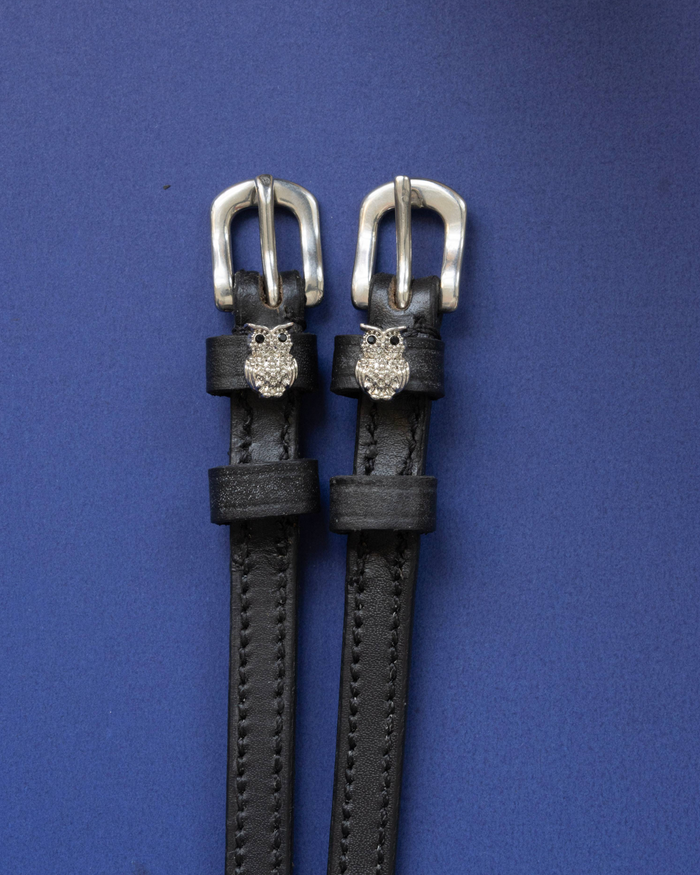 Owl rhinestone spur straps in black leather with silver buckles on a royal blue background