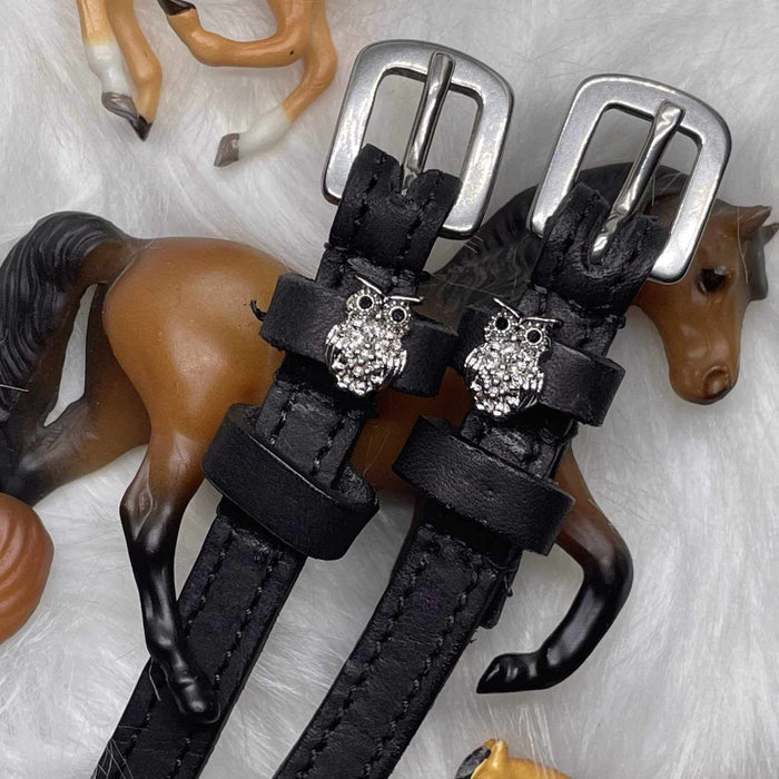 Silver crystal owl spur straps styled with toy horse figurines on white fur