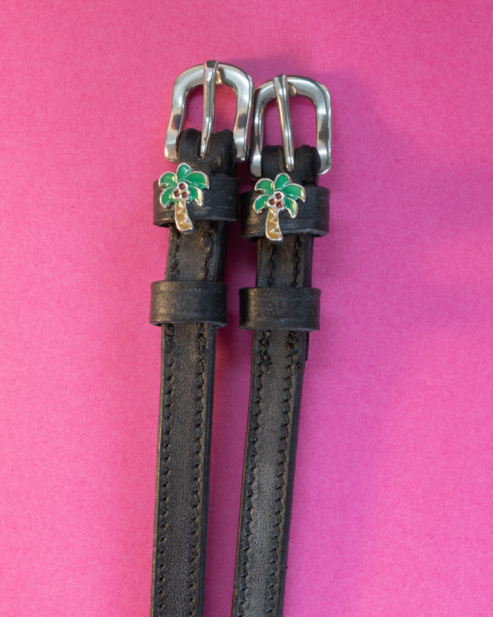 Black leather ManeJane spur straps with green palm tree charms on hot pink