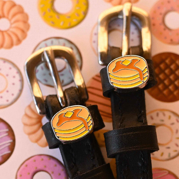 Detail of gold buckles and pancake charms on ManeJane spur straps over a donut print