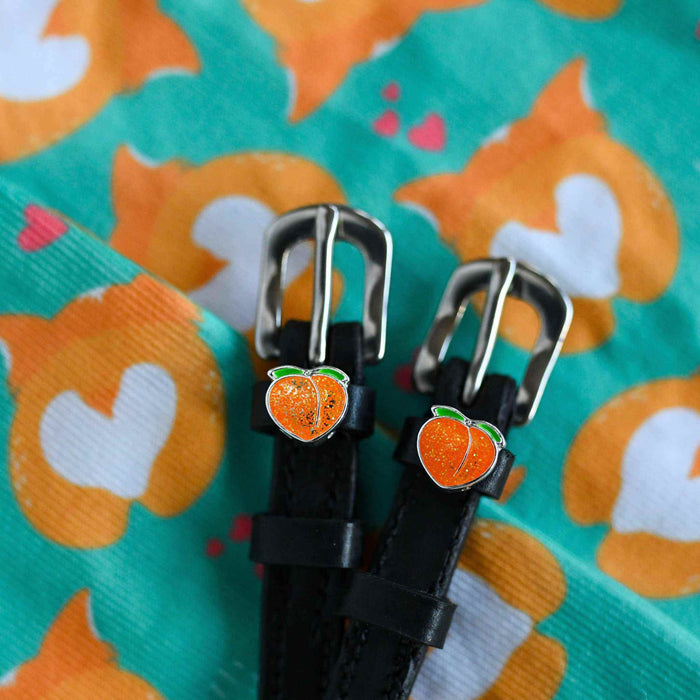 Black leather peach charm spur straps on a teal patterned fabric