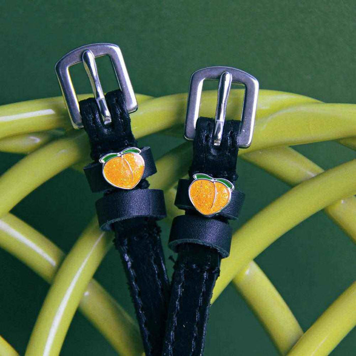 Black leather peach spur straps draped over a yellow coil on green