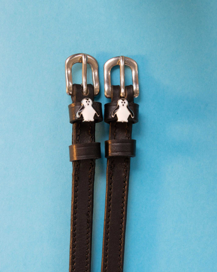 Penguin ManeJane spur straps with the signature Penguin charm, shown on a light blue background