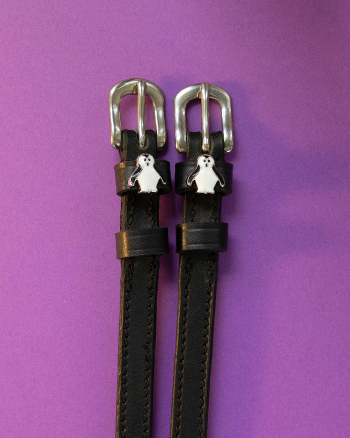 Penguin ManeJane spur straps with the signature Penguin charm, shown on a purple background