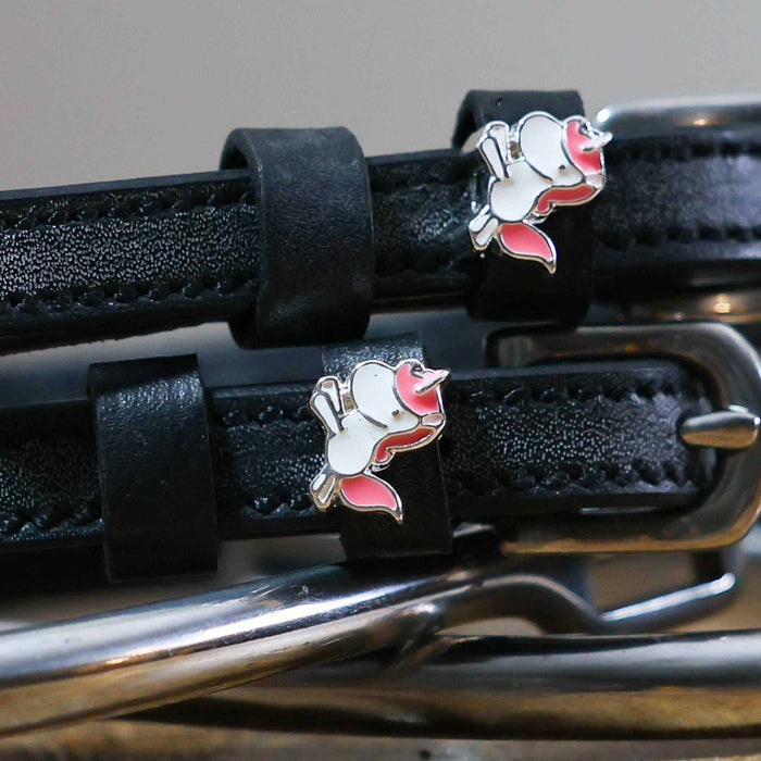 Close-up of white-and-pink unicorn charms on black leather spur strap keepers
