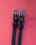 Black leather ManeJane spur straps with silver buckles and green pickle charms on coral red