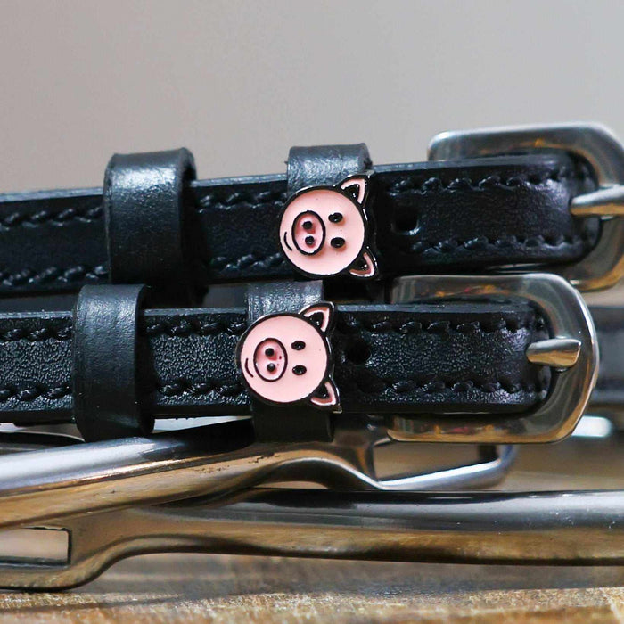 Close-up of pink pig-face charms on black leather spur strap keepers