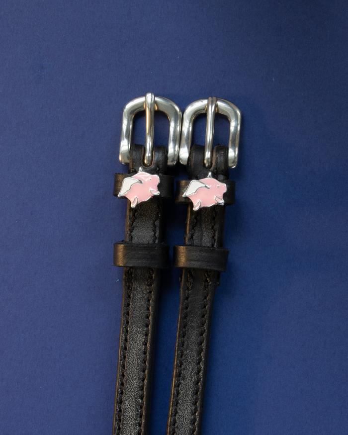 Black leather ManeJane flying pig spur straps on a navy background