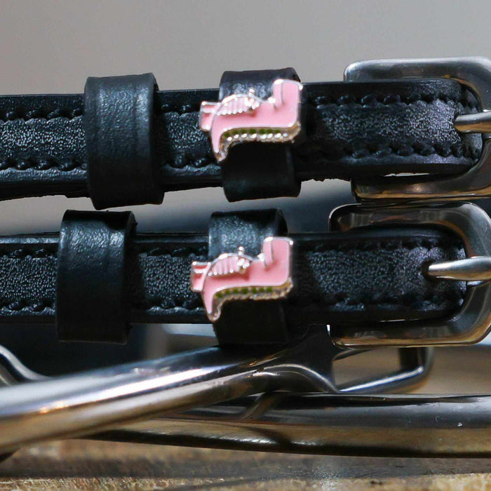 Close-up of pink T-rex dinosaur charms on black leather spur strap keepers