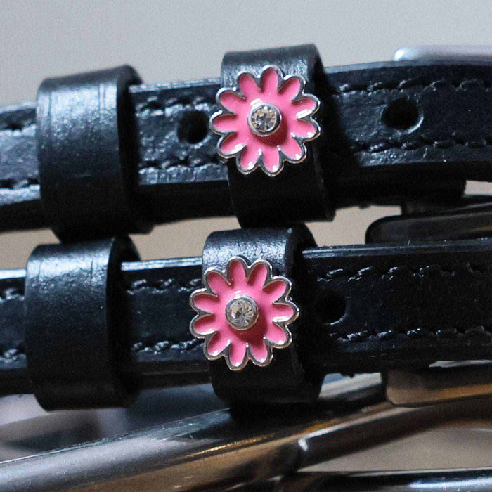 Close-up of pink daisy charms with rhinestone centers on black leather spur straps