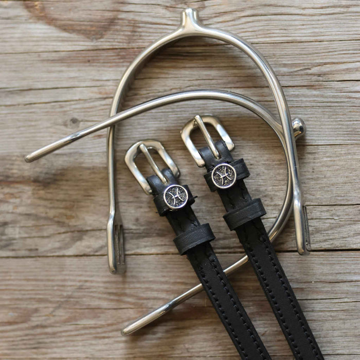 Black leather Pisces spur straps and a silver spur on weathered wood planks