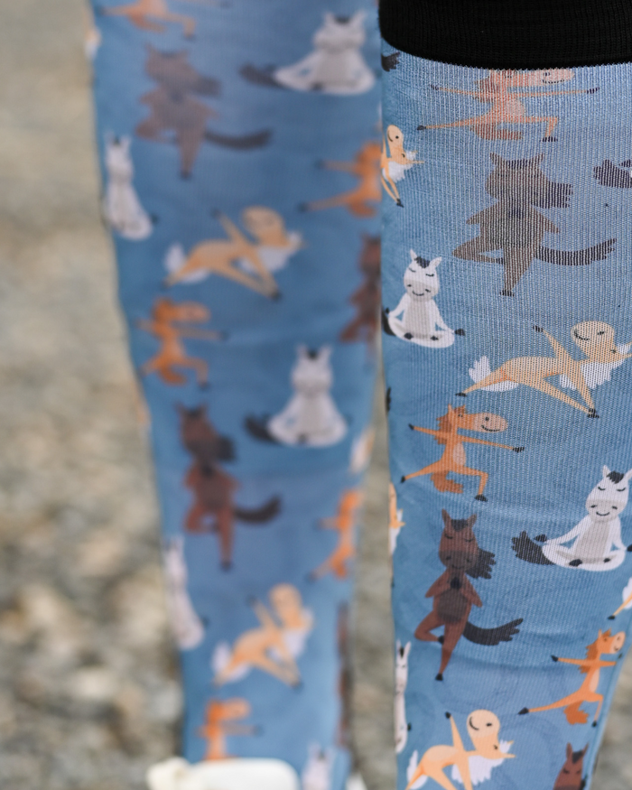 Close crop of the Pony Pilates boot sock print, horses stretching through yoga poses on soft blue