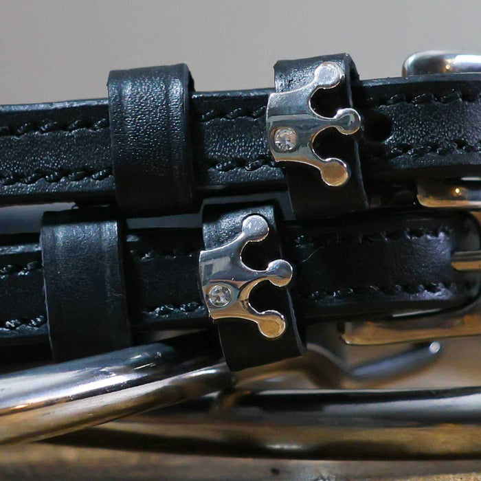 Close-up of silver crown charms with rhinestones on black leather spur strap keepers
