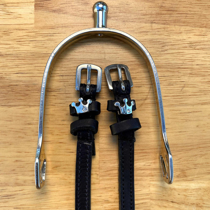 Queenie crown spur straps hung from a silver bracket on a wooden tabletop