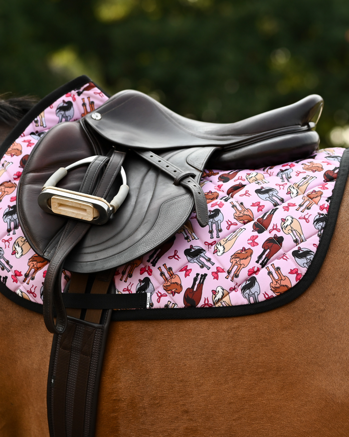 Light pink Red Ribbon Girlies pad under a brown close-contact saddle and stirrup, black binding