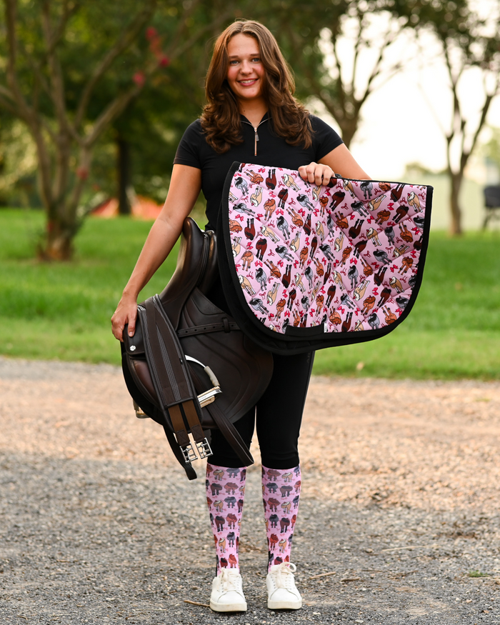 Red Ribbon Girlies saddle pad carried at the barn, pink quilting printed with horse hindquarters tied with red bows