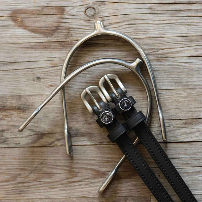 Sagittarius charm spur straps laid with a silver spur on weathered wood planks