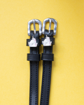 Black leather ManeJane spur straps with silver unicorn head charms and buckles on yellow