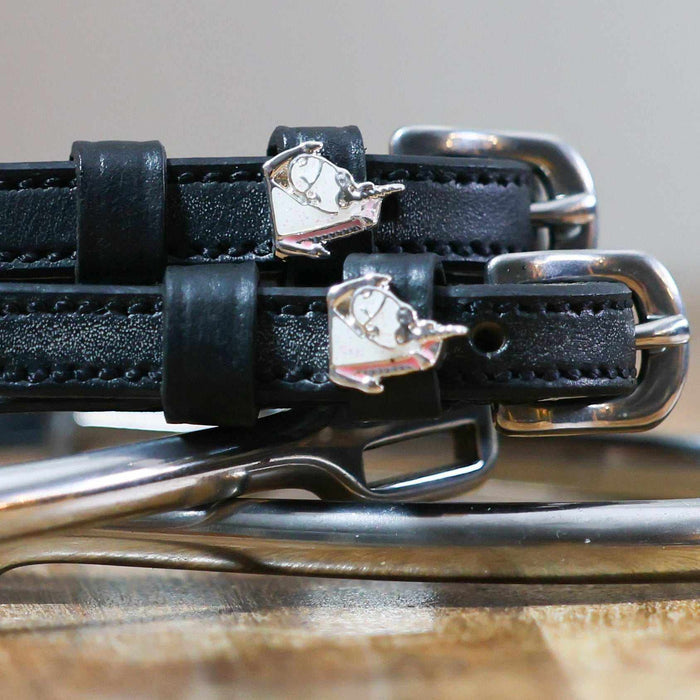 Close-up of silver enamel unicorn charms on black leather ManeJane spur strap keepers
