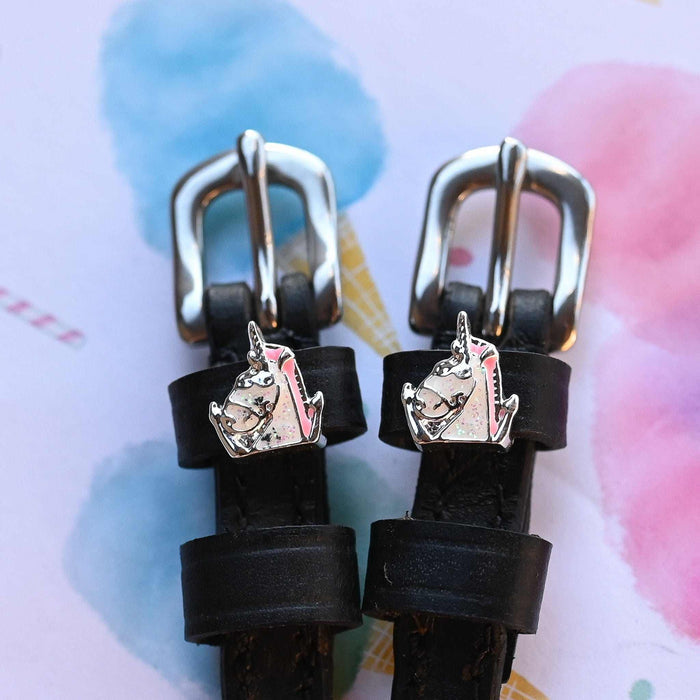 Silver unicorn head charms on black leather spur straps over a pastel watercolor background