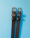 Black leather ManeJane spur straps with silver buckles and round Scorpio zodiac charms on blue