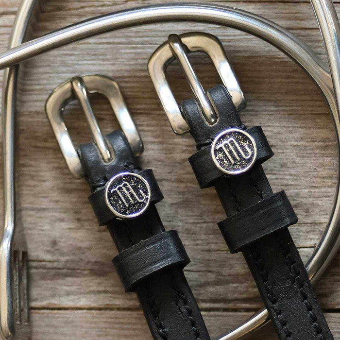 Silver Scorpio medallion spur straps buckled, close-up on a weathered wooden surface