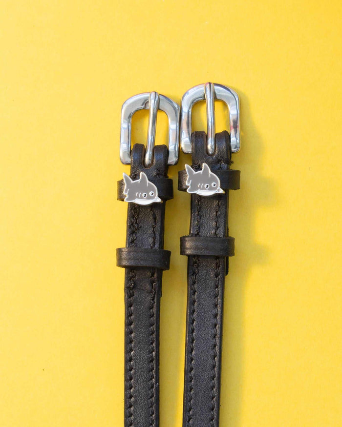Black leather ManeJane shark charm spur straps with silver buckles on yellow