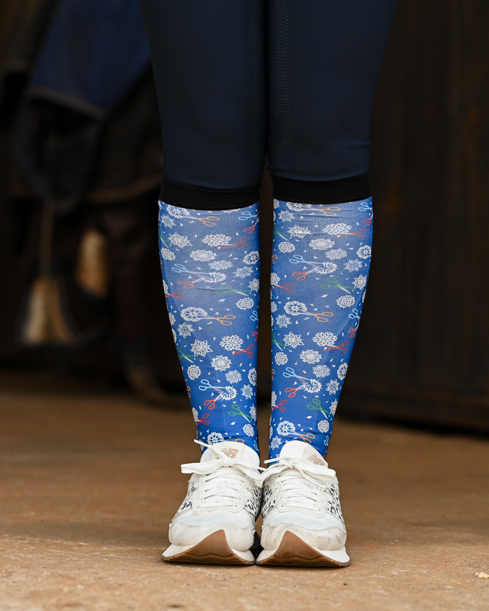 Shear Magic boot socks seen from the front, cobalt blue ground scattered with white clip rosettes and coloured scissors
