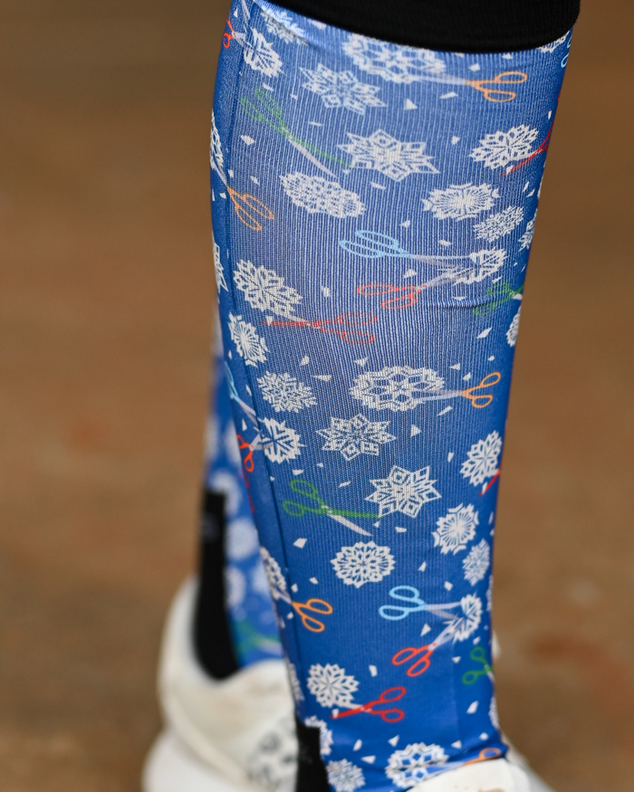 Close crop of the Shear Magic boot sock print, white clip rosettes and coloured scissors on cobalt blue