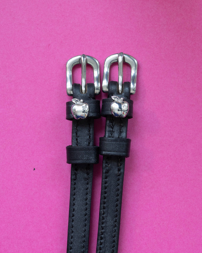 Black leather ManeJane spur straps with silver buckles and 3D silver apple charms on pink