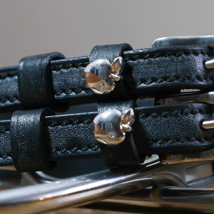 Close-up of shiny silver apple charms on black leather spur strap keepers