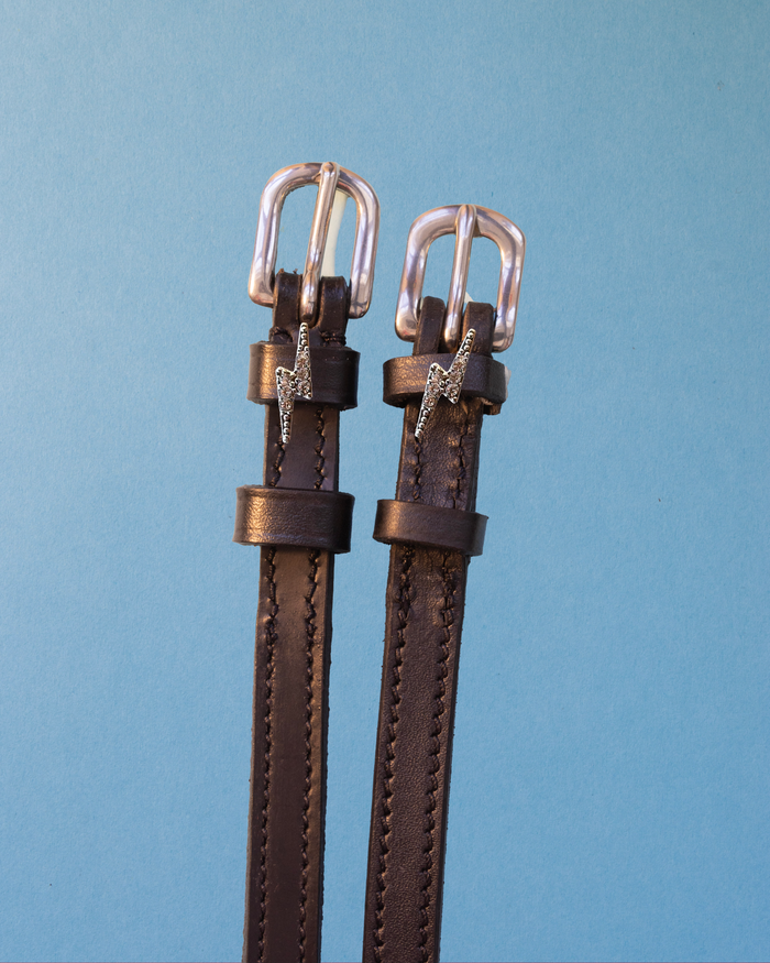 Bling bolt charm spur straps on brown leather with silver buckles on light blue