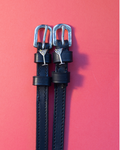 Black leather ManeJane spur straps with silver martini glass charms flat-laid on coral
