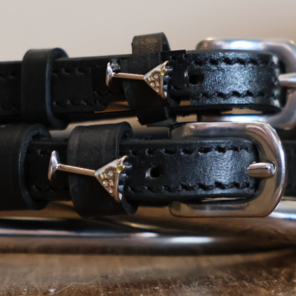 Close-up of silver martini glass charms on black leather ManeJane spur strap keepers