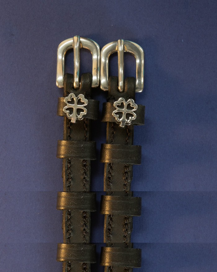 Black leather ManeJane spur straps with silver openwork four leaf clover charms on navy