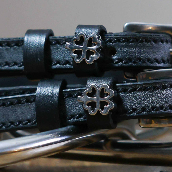 Close-up of silver outline clover charms on black leather ManeJane spur straps
