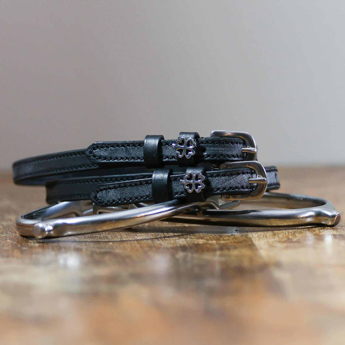 Coiled black leather clover spur straps on a silver spur, openwork silver clover charms