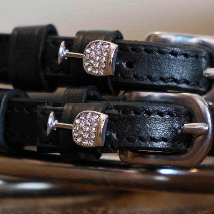 Close-up of rhinestone wine glass charms on black leather spur strap keepers