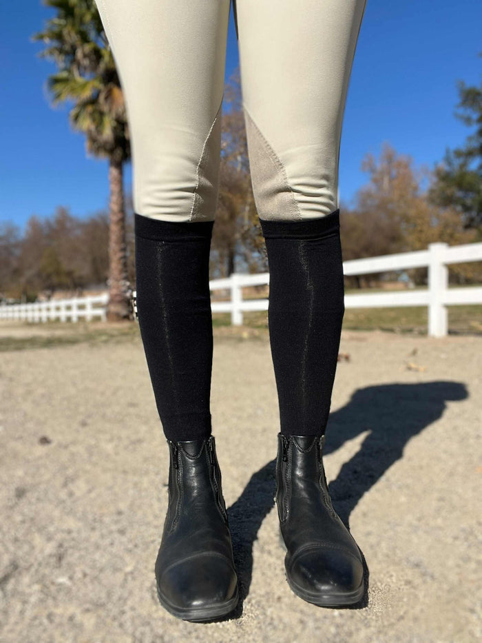 Not So Basic Black equestrian boot socks worn with riding boots and beige riding pants outdoors