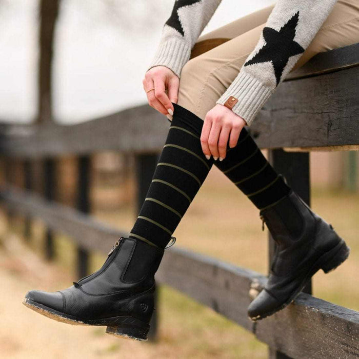 black knit boot socks with green stripes worn with black equestrian boots outdoors