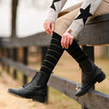 black knit boot socks with green stripes worn with black equestrian boots outdoors